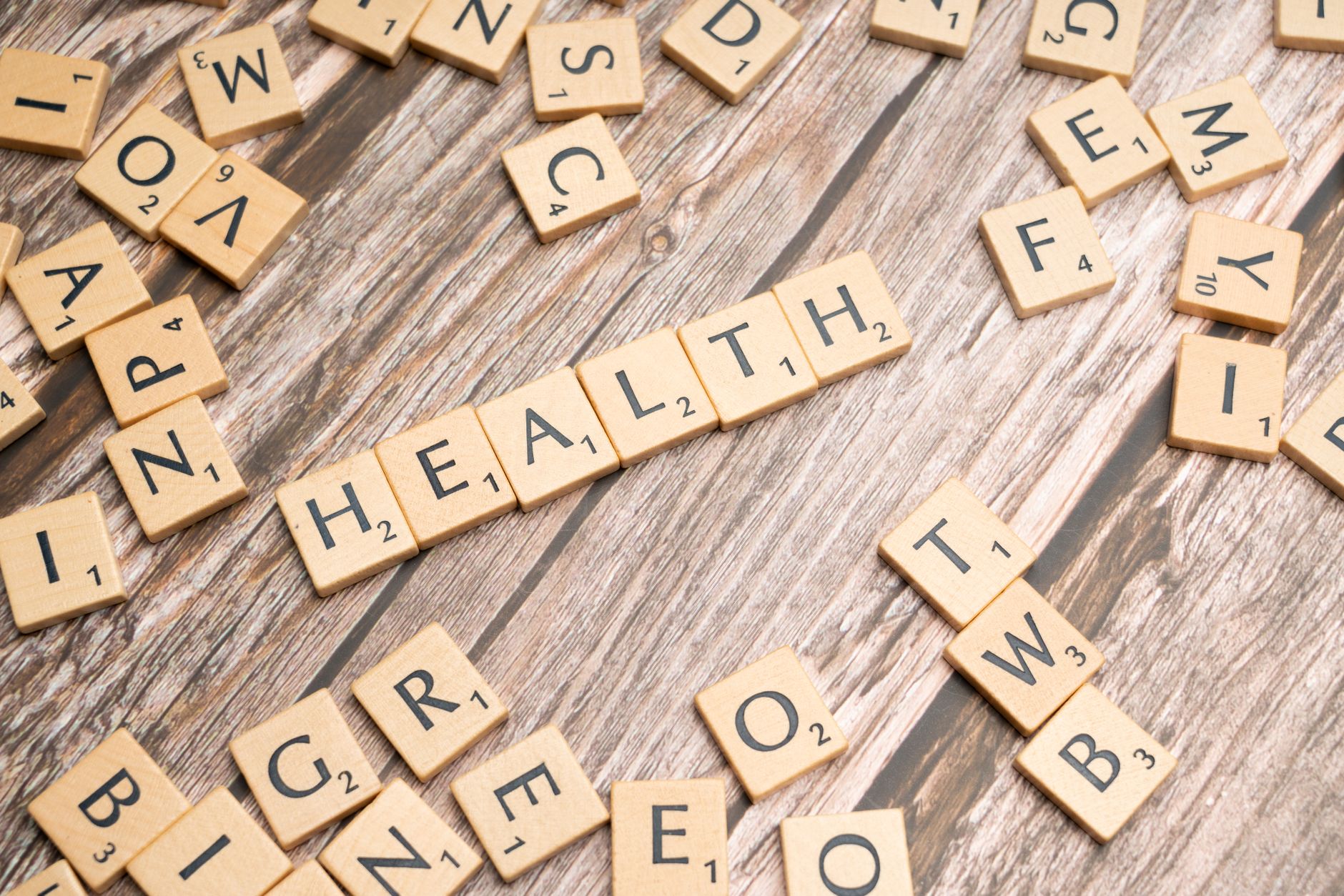 Scrabble tiles spelling 'HEALTH' on wooden surface, symbolizing wellness. — Benefits of Consuming Gin for Your Health