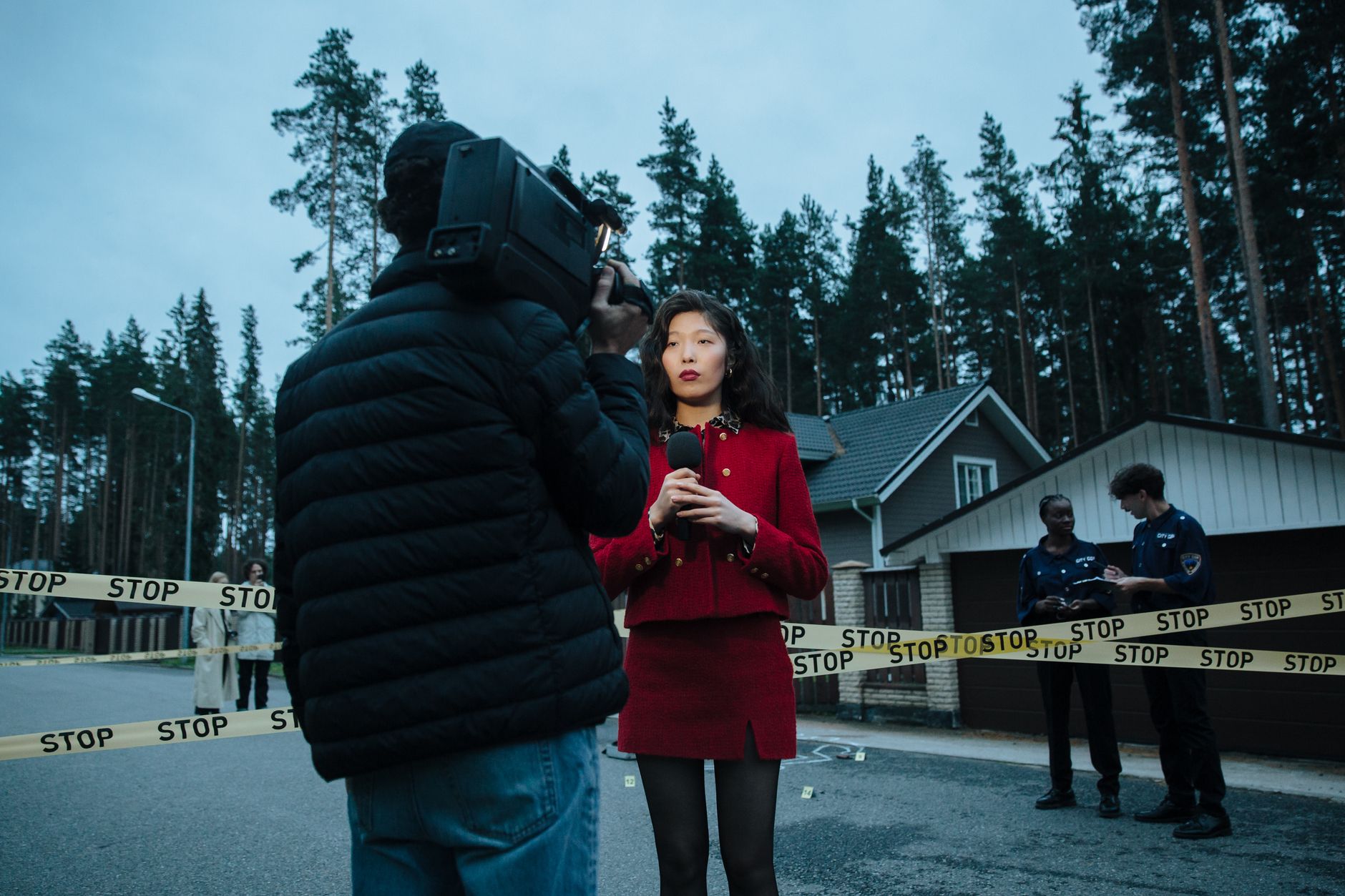 A female journalist reports live from an outdoor crime scene, flanked by police officers and media personnel. — Best thin fil