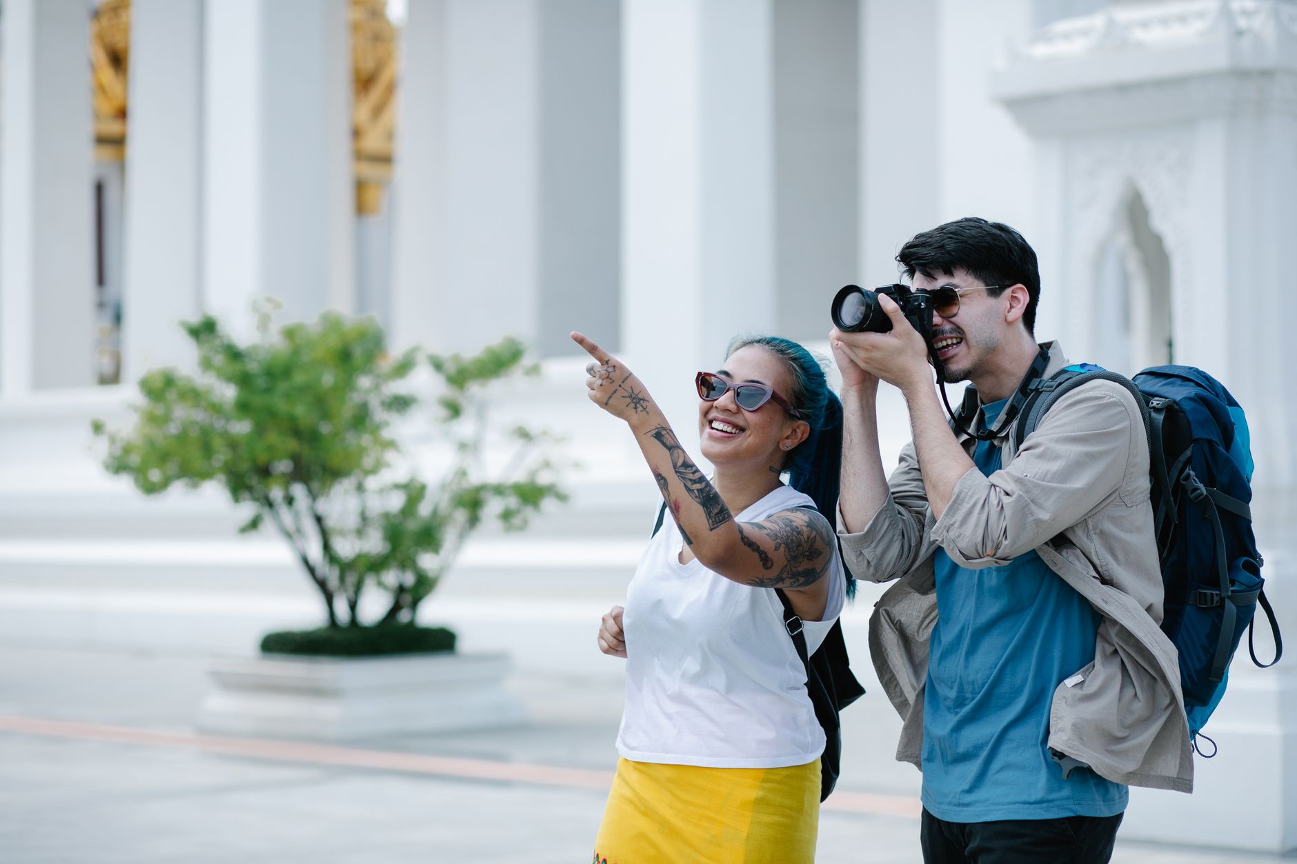 A smiling man and woman explore architectural landmarks with a camera, embracing travel and photography. — Booking Your Perso