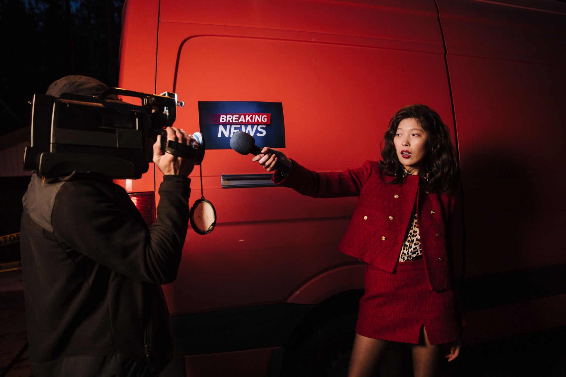 Asian female reporter with cameraman conducting a nighttime news broadcast beside a news van. — Choosing the Right Private Ph