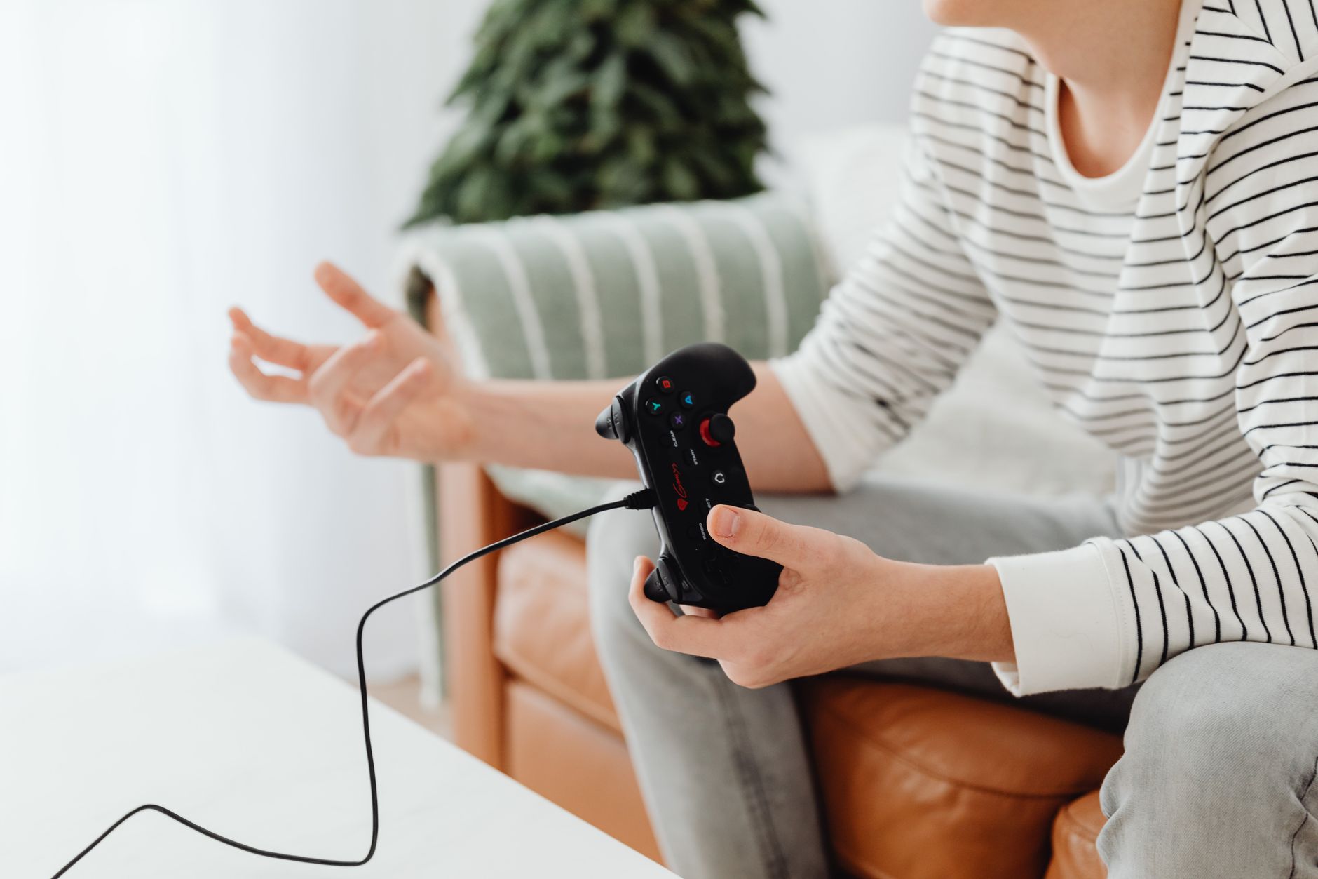 Close-up of a person playing video games at home with a wired controller on a couch. — Get Ready to Experience the Incredible