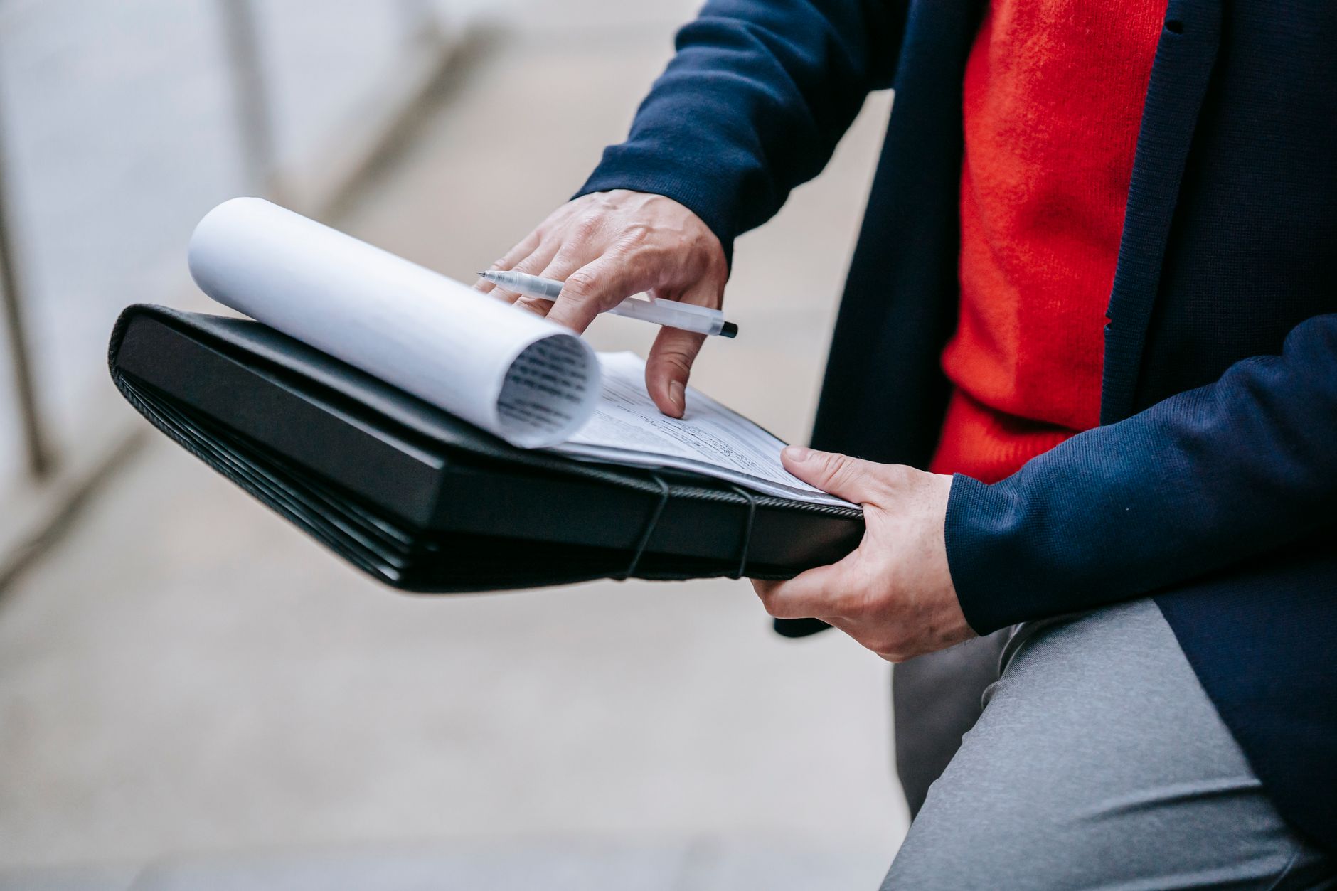 Close-up of a professional person reviewing documents outdoors. Engaged in work with focus on writing materials. — How To Beg