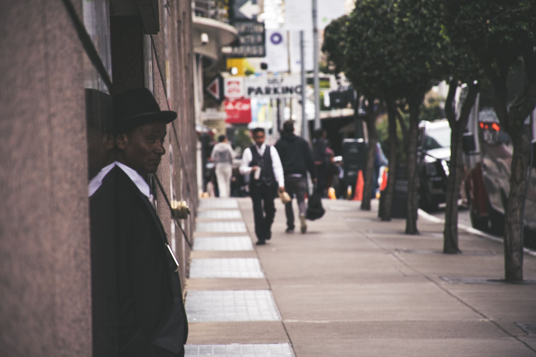 A man in a suit and hat leans against a city building, observing pedestrians. — How to Choose the Right B2B Services for Your