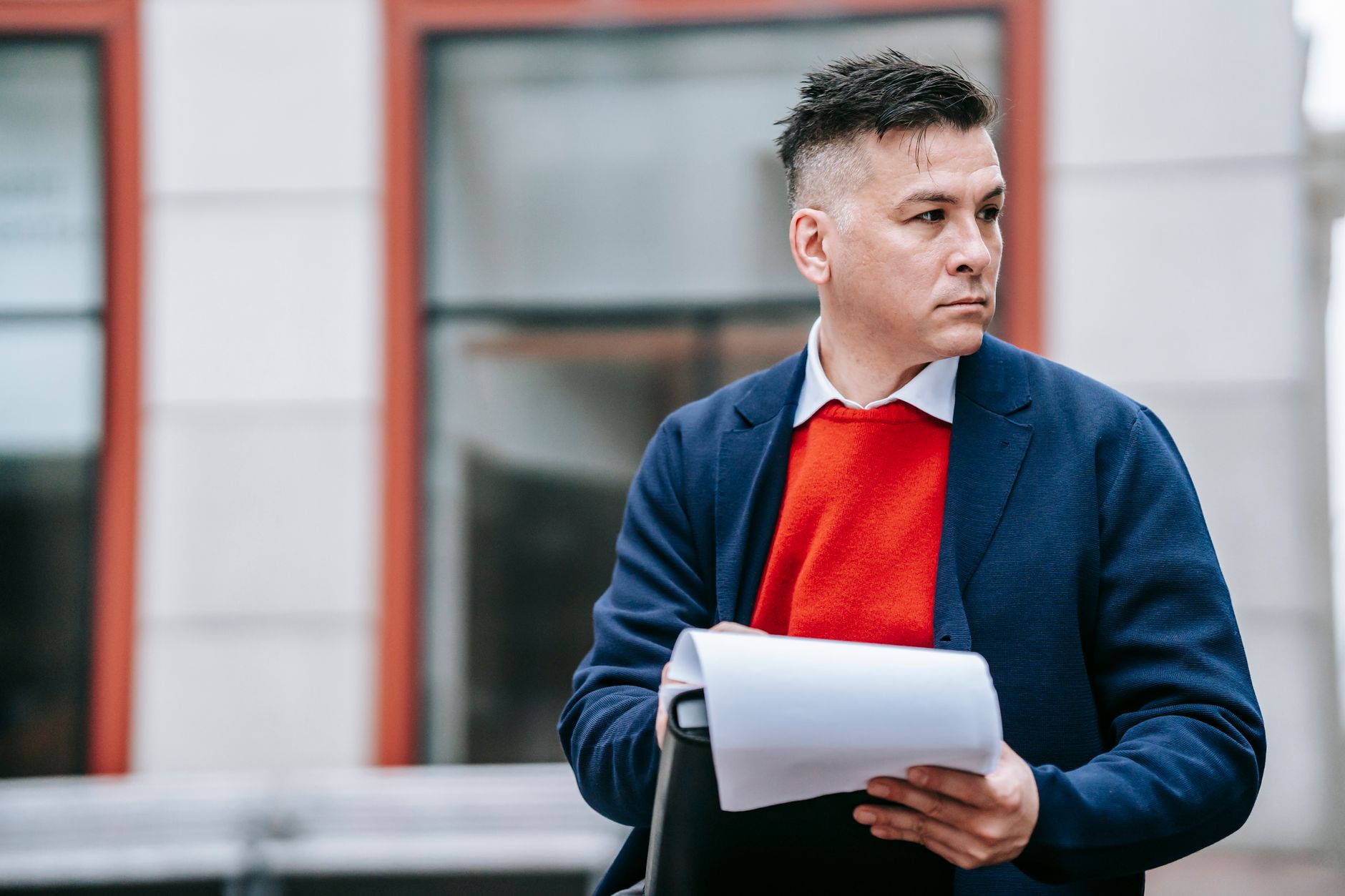 A serious man holding papers, dressed professionally in an urban environment. — How To Understand More About Business