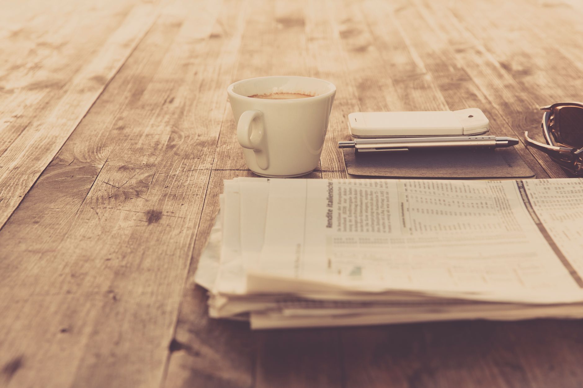 A warm vintage morning setup with coffee, newspaper, and smartphone on wooden table. — Mental Health and Medicare Advantage: