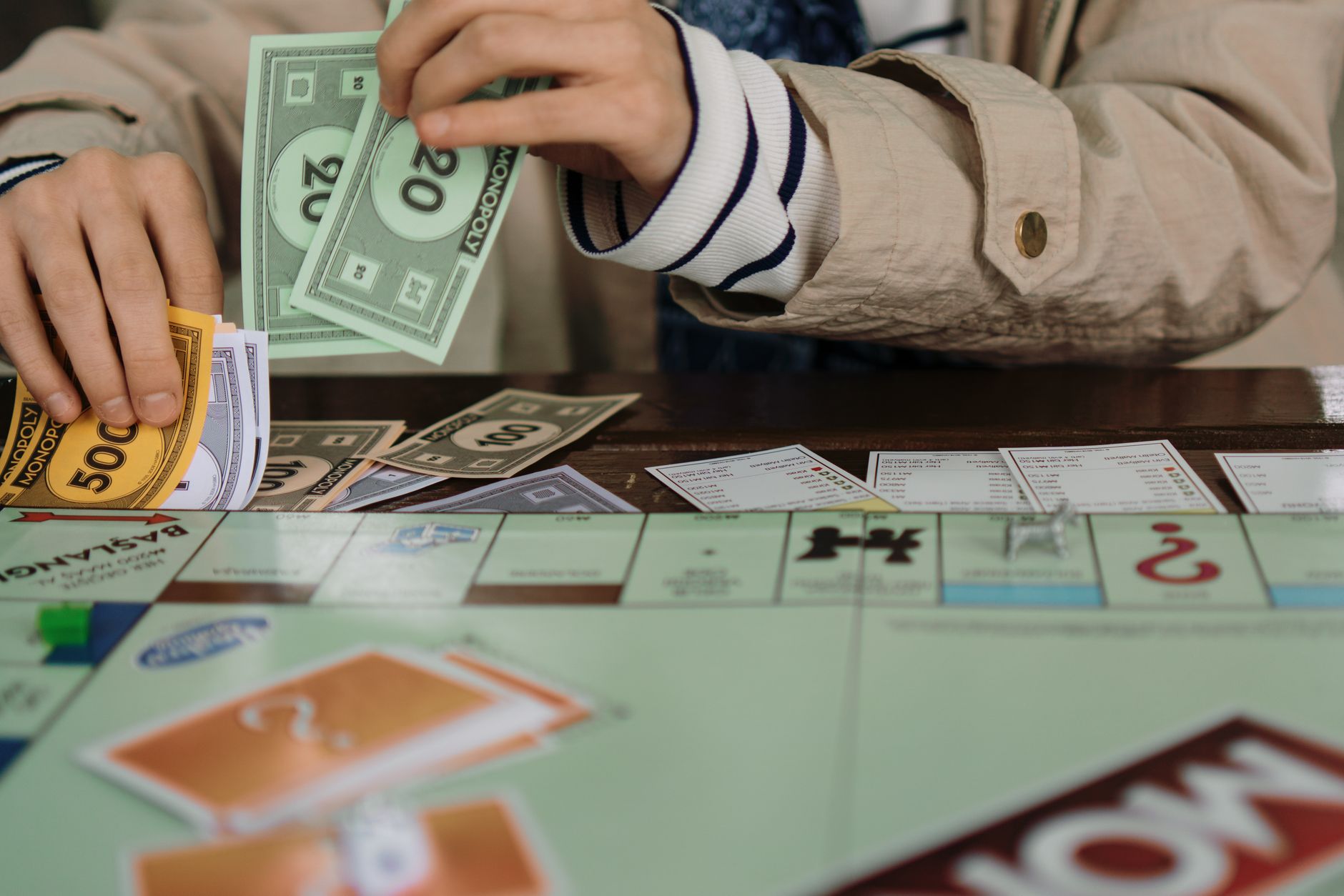 Hands counting Monopoly money during a board game session, highlighting fun and strategy. — Playing Games Becomes Fun WithVal