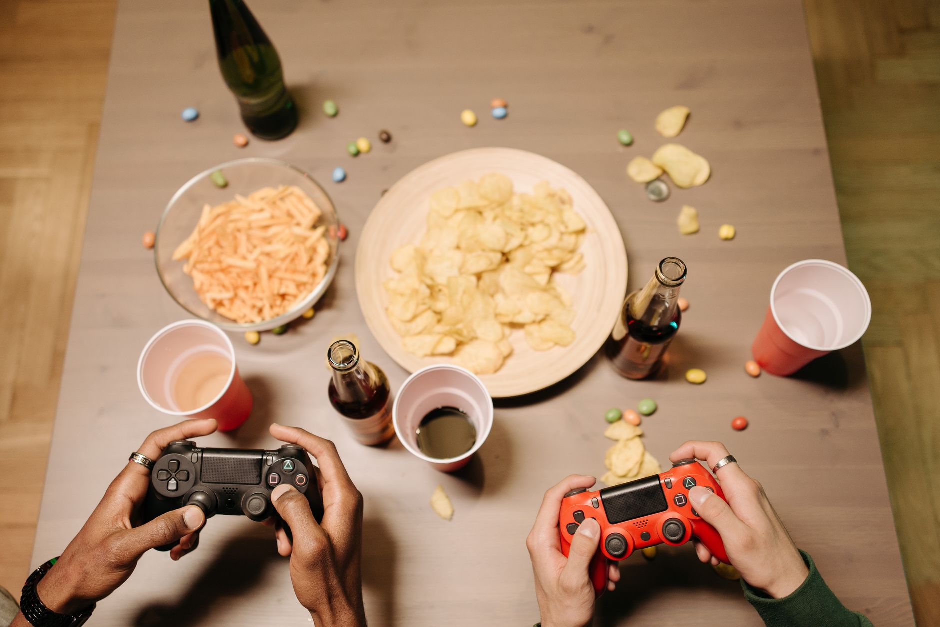 Two gamers playing video games with snacks and drinks on table, a perfect setup for gaming night. — Successful Your Baccarat