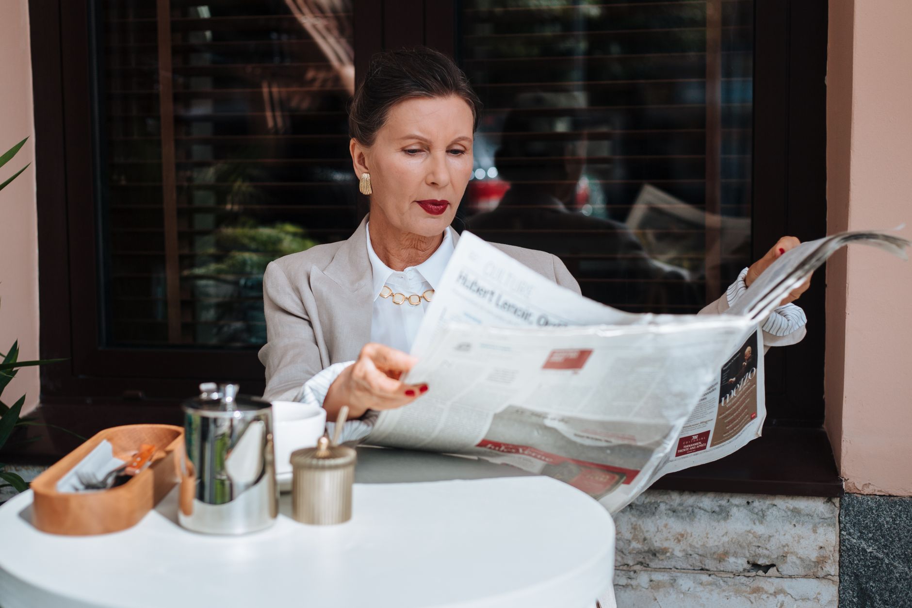 Sophisticated woman enjoying her morning newspaper at a cozy outdoor cafe. — Sunflowers In Houston, TX