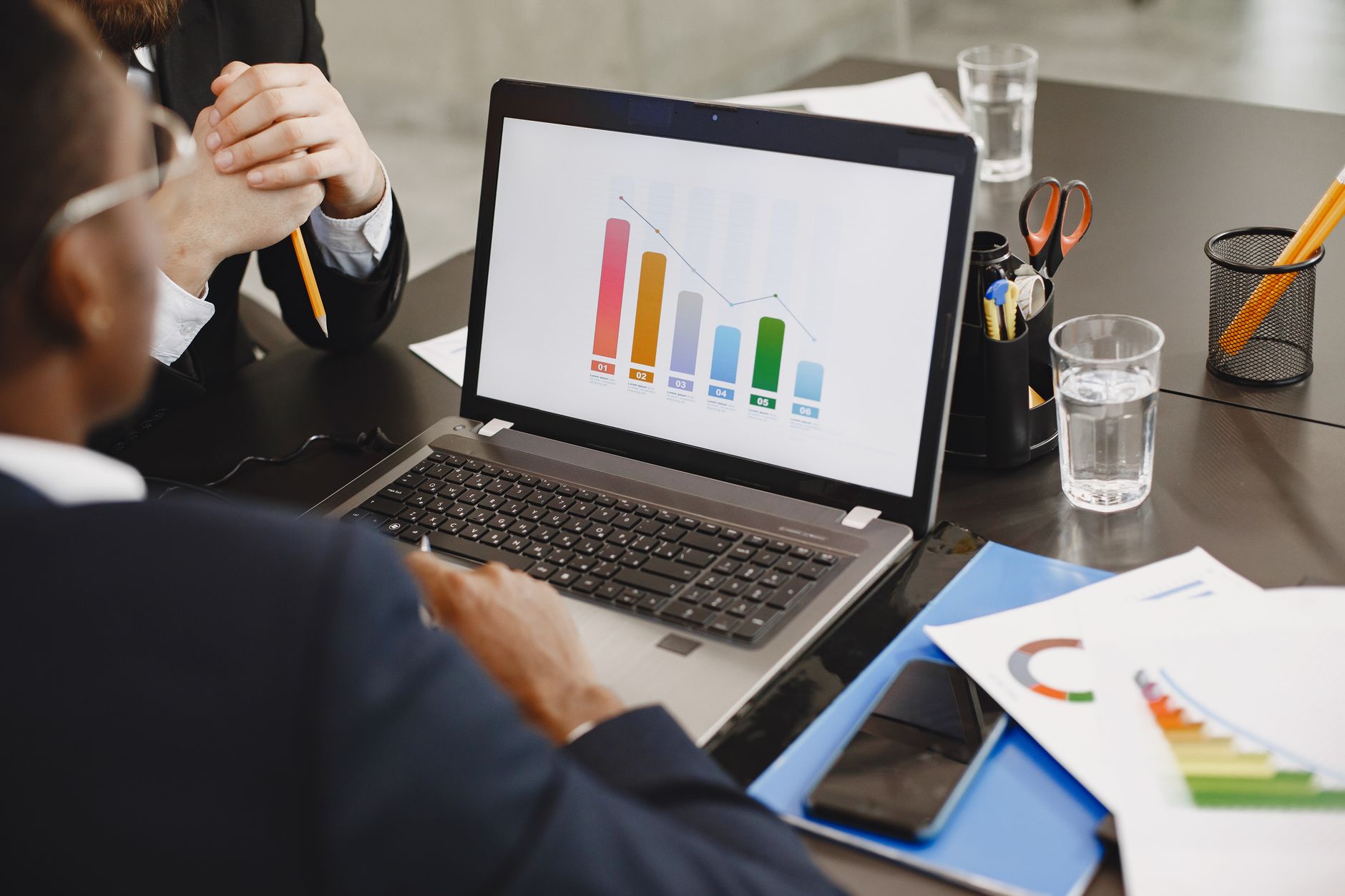 Two professionals analyzing a business graph on a laptop during a meeting. — Unlocking the Future of SEO: A Deep Dive into YA