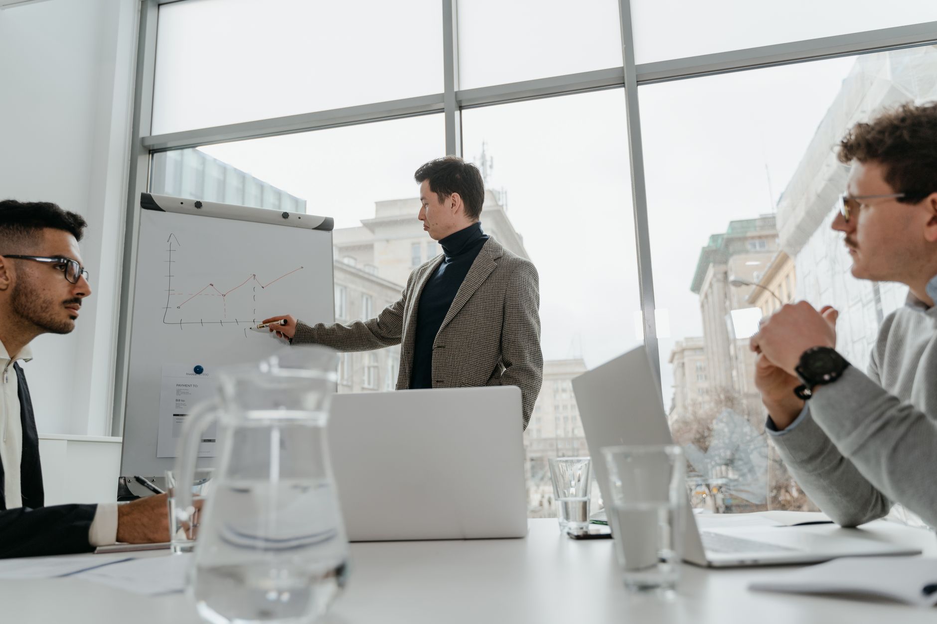 Professionals engaged in a collaborative business meeting with charts and laptops in a modern office setting. — What makes Wh