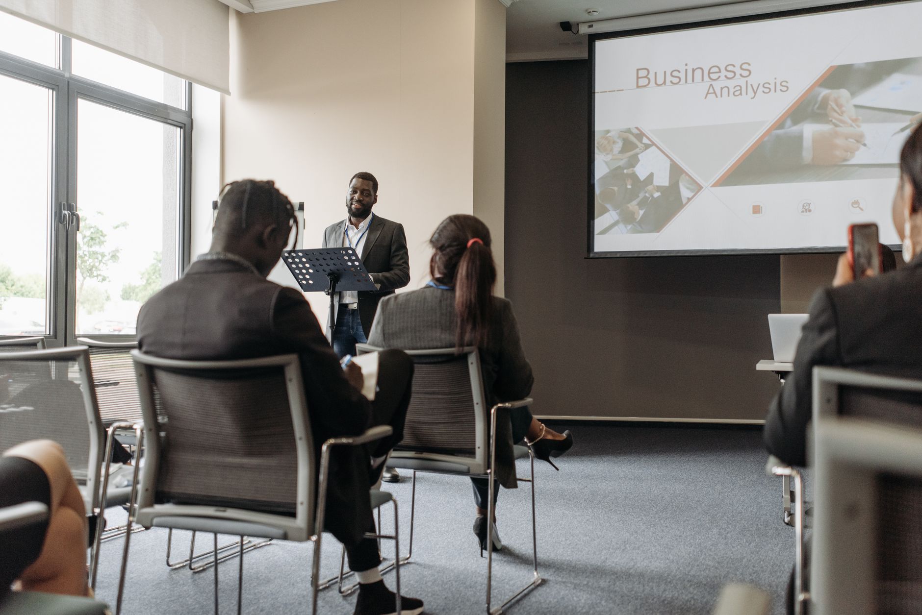 A business professional delivering a presentation in a conference room with diverse attendees. — Why IPTV Smarters Pro is the