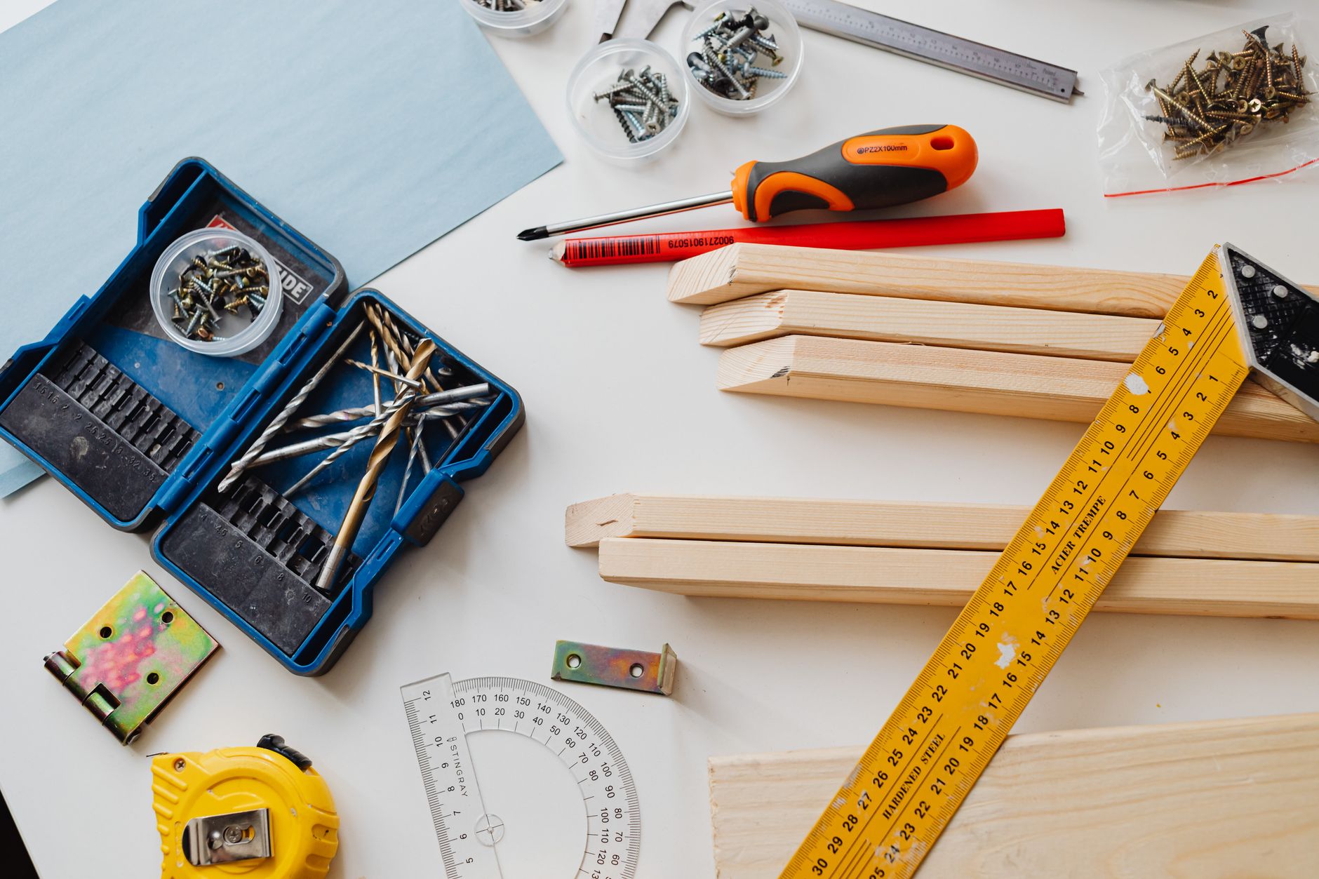 A top view of various woodworking tools and materials on a white table. — You Must Know These Things When Searching For Homes